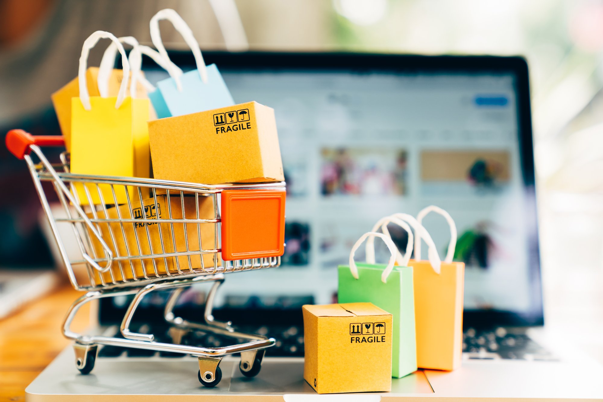 Kuvassa miniostoskärry ja paketteja tietokoneen ruudun edessä